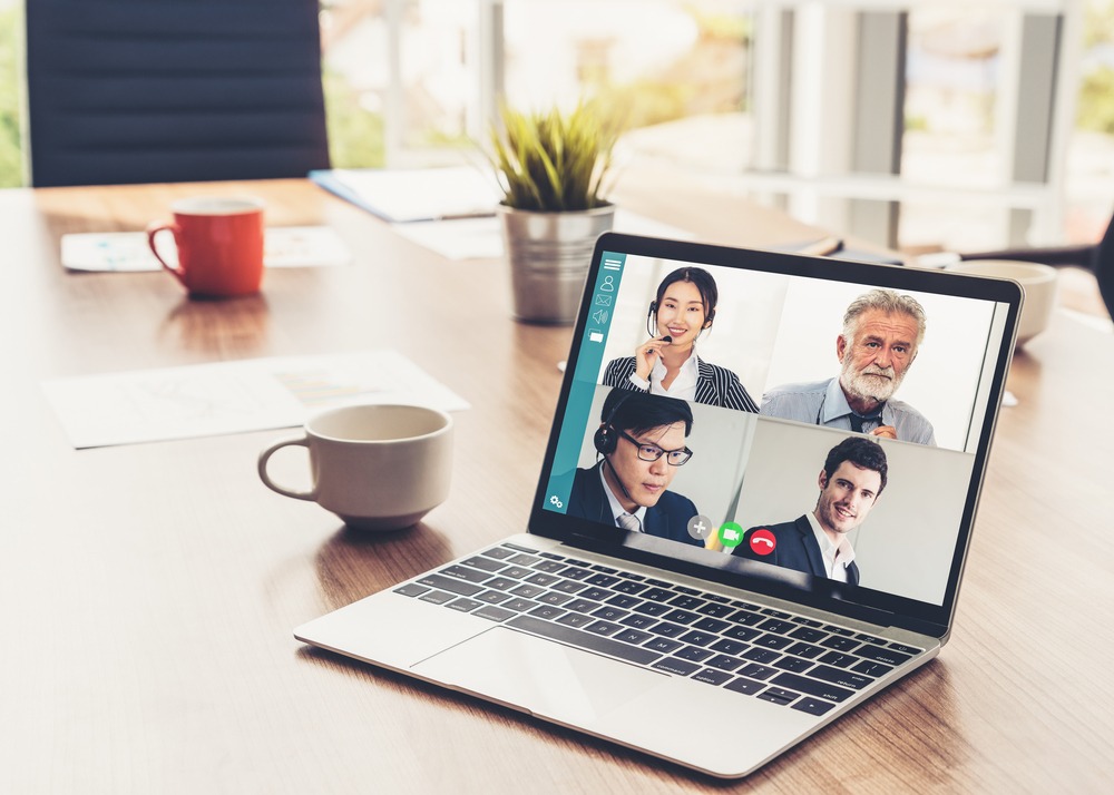 Stock photo of a laptop with the screen split into four mini images of different business people an online call